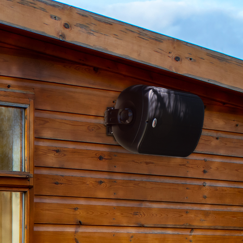 A black CS500 outdoor speaker mounted over wood siding just below the roofline