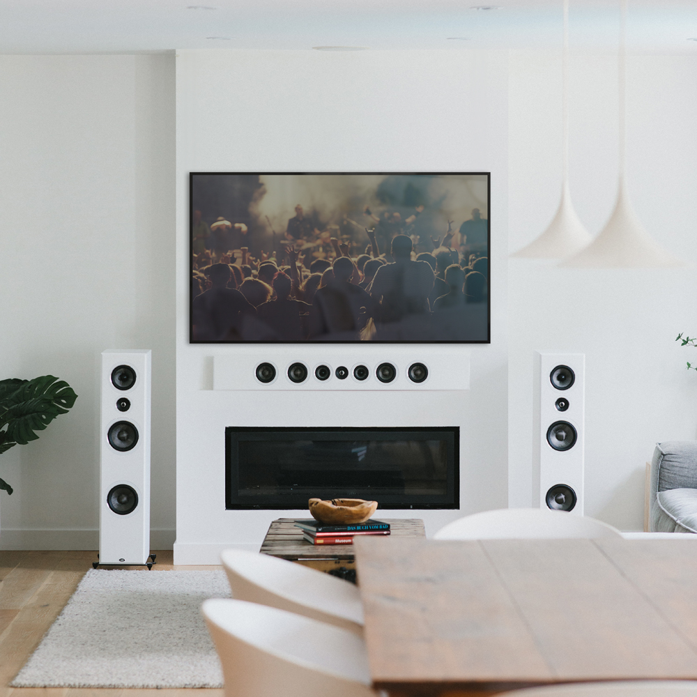 A white PSB PWM3 speaker mounted horizontally on a wall below a large TV