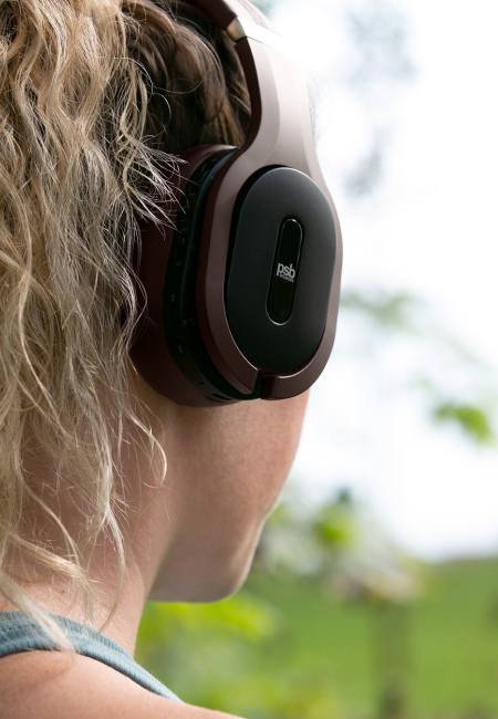 A woman listening to music on PSB M4U 8 MKII brown headphone while jogging.